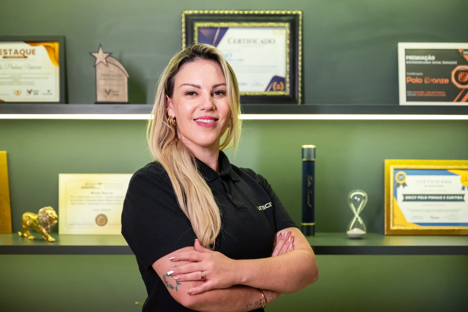 Eliane Pinheiro de Oliveira, diretora do Polo Unicive Pinhais, ao lado da estante de prêmios e reconhecimentos